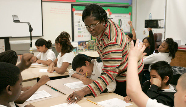 Kennedy Elementary School teacher Marjorie Hunt-Bluford works with her fifth-grade students on math problems. Hunt-Bluford is one of more than 7,000 Houston Independence School District teachers to earn a merit pay bonus in 2006. (AP/Pat Sullivan)