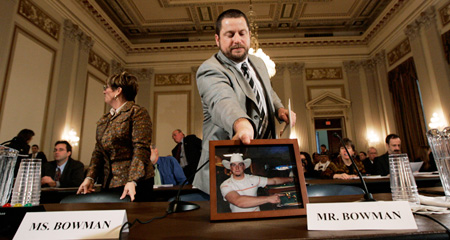 Mike Bowman picks up a photo of his son Tim, who committed suicide after serving in the Iraq war, after testifying at a House Veterans' Affairs Committee hearing on veterans' mental health issues. (AP/Susan Walsh)