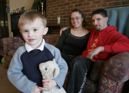 Two year-old Austin Shea—a recipient of public health benefits—poses as his parents look on. His  benefits were delayed for months as they waited for a copy of his birth certificate from their home state. (AP/David Kohl)