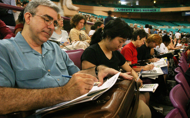 Jay Schwartz of West Caldwell, N.J., left, fills out a form during an orientation program for first time New York City public school teachers at Madison Square Garden in New York. (AP/Tina Fineberg)