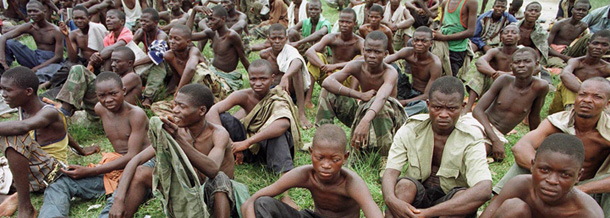 Congolese men detained by Congolese rebels as prisoners sit in a field awaiting a process where most will be converted into rebel soldiers. Eastern Congo is one of many places where crimes against humanity are a daily reality. (AP/Brennan Linsley)