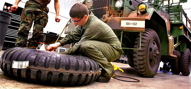 A specialist in the Maintenance Company of the Illinois Army National Guard change tires for a 2.5-ton, M35A2 truck. The Illinois Army National Guard is only one of many units in the United States and deployed in Iraq that are facing significant equipment shortages. (AP/Seth Perlman)