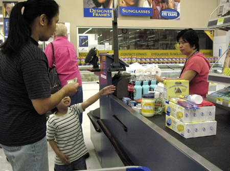 A woman pays for her groceries at a store in San Leandro, CA. As home energy and gasoline costs rise, more Americans are forced to cut spending on basic necessities such as food, with low-income families the most affected. (AP/Ben Margot)