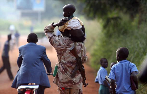 A soldier from the Sudan People's Liberation Army carries his son in the streets of Yei, Juba, Southern Sudan. Almost half the displaced in Southern Sudan are children. (IRIN/Manoocher Deghati)