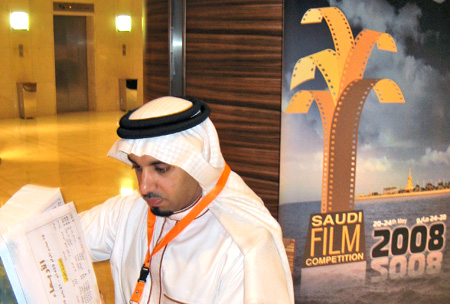 Atef al-Ghanem, head of the first Saudi Film festival's cultural committee, makes preparations in front of a poster for the event. (AP/Donna Abu-Nasr)