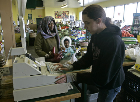 A cashier rings up a customer at a produce store in Albany, NY. The rise in food prices since last year is only one of many factors adding to the hardship of U.S. workers. (AP/Mike Groll)