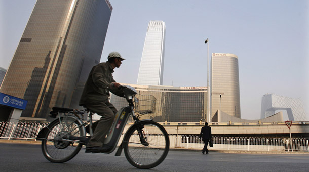 A cyclist and man pass by the central business district in Beijing on November 10, 2008. China announced a domestic stimulus package earlier this week of 4 trillion yuan, which will help to avoid further global economic decline. (AP/Ng Han Guan)