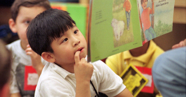 Huy Nguyen, 5 años, alumno del jardín de la infancia (kindergarten) de la Escuela Primaria David Reece de Sacramento, California, sigue el relato de un libro de cuentos que se le lee a la clase. (AP/Rich Pedroncelli)