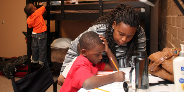 A woman helps her son with his homework at Eden Village, a division of City of Refuge, which provides housing for homeless women and their children in Atlanta. A new report from the U.S. Conference of Mayors shows sharp increases in homelessness in 25 major U.S. cities. (AP/Jenni Girtman)