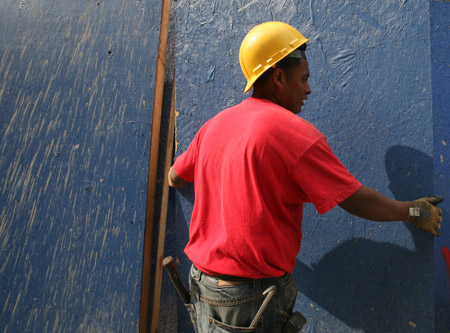 A worker moves a sheet of plywood at a New York construciton site earlier this year. "Greening" the current housing stock would provide employment opportunities for the many construction workers laid off this year while improving the quality of the stock. (AP/Jim Cole)