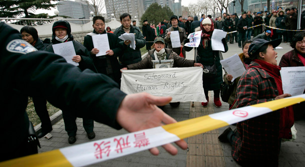 Police cordon off the area where protesters show letters detailing their complaints, displaying a banner that reads "Safeguard human rights" outside of the Foreign Ministry in Beijing. (AP/Elizabeth Dalziel)
