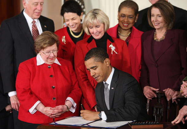 Surrounded by members of Congress, President Barack Obama signs the Lilly Ledbetter Bill with Lilly Ledbetter, at center, behind Obama. (AP/Ron Edmonds)