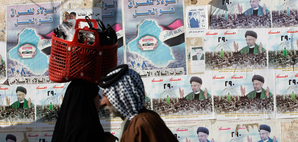 Iraqis pass campaign posters for the upcoming provincial election in the Shiite city of Najaf. (AP/Alaa al-Marjani)