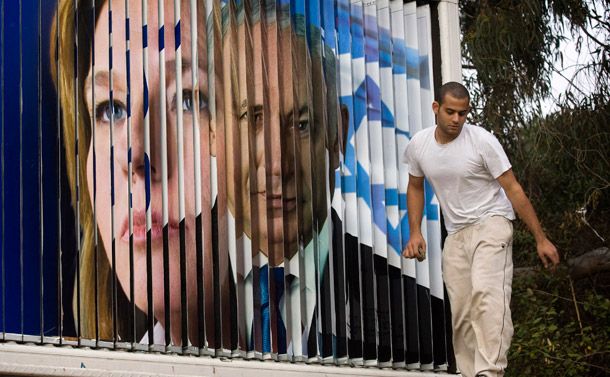 A worker walks next to a rotating sign showing campaign signs for Israeli Foreign Minister and Kadima Party leader Tzipi Livni and Likud Party leader Benjamin Netanyahu.
<br /> (AP/Sebastian Scheiner)