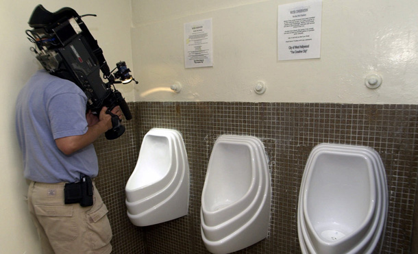 An unidentified news photographer videotapes touch-free, waterless urinals in the men's room at Plummer Park in West Hollywood, CA. As Congress develops an omnibus energy bill for later this year, it should include incentives for consumers, businesses, and water providers to conserve water and thereby reduce energy consumption. (AP/Nick Ut)