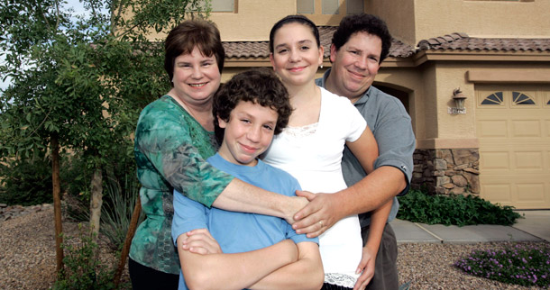 A family poses outside of the home, which they were able to keep after getting their lender to modify their loan. (AP/Matt York)