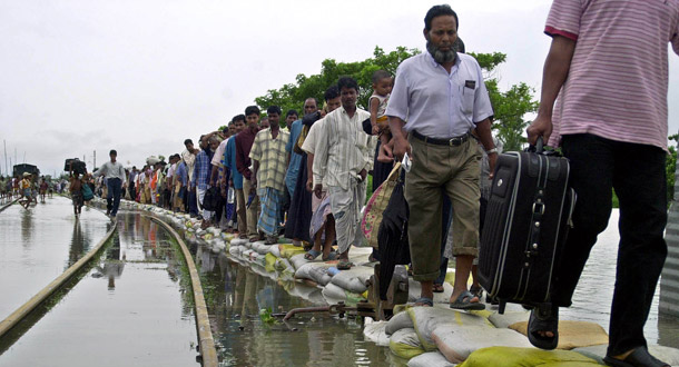 Bangladeshi train passengers walk over sand bags placed near a flooded rail track as they try to reach a ferry station to cross the swollen Jamuna River. Providing financial assistance for the most vulnerable countries to use in adapting to global warming's effects is responsible and a good long-term investment. (AP/Pavel Rahman)