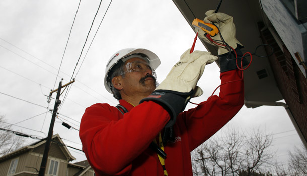 Gary Kawano installs a new meter outside a home in Boulder, CO, on November 25, 2008, as part of the smart electrical grid system being put into place in the university city. (AP/David Zalubowski)