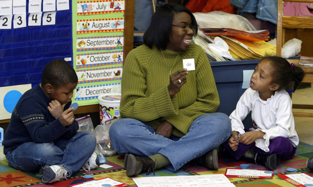 Teacher Angela Lively, center, plays word bingo with Willie Brown III, left, and Kayla Johnson in her Indianapolis kindergarten classroom. Lively keeps a box of shoes so poor children can get a new pair when their old shoes won't fit. Full refundability of the Child Tax Credit would enable it to help more low-income families with child-rearing costs. (AP/Michael Conroy)