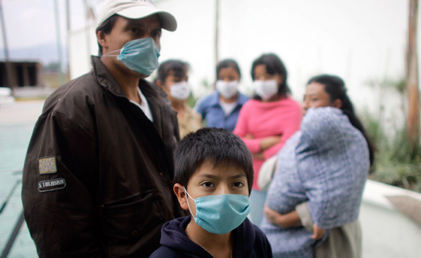 People wearing face masks stand near the home of Gerardo Leyva, one of the first victims of swine flu, in the town of Xonacatlan, Mexico. (AP/Miguel Tovar)