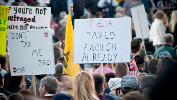 Protesters hold signs at a Fox News-promoted tax day "tea party" yesterday in Birmingham, Alabama. (Flickr/ <a href=