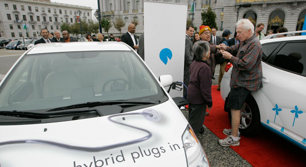 A group of people react after looking inside of a hybrid electric vehicle's gas tank parked on display outside San Francisco's City Hall after a $1 billion network of electric car recharging stations that will dot the Bay area highways was announced on November 20, 2008. (AP/Eric Risberg)