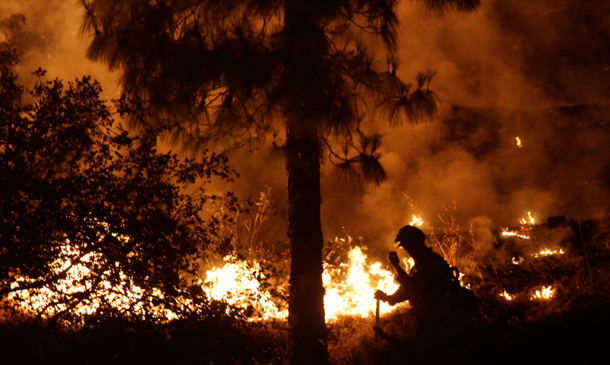 A firefighter works the line of a wildfire near Tujunga, CA, Tuesday, Sept. 1, 2009. A relentless Southern California wildfire raged Tuesday with 53 homes up in smoke, thousands more threatened and new rounds of evacuations as towering flames crackled close to neighborhoods on the northern and southern flanks. (AP/LM Otero)