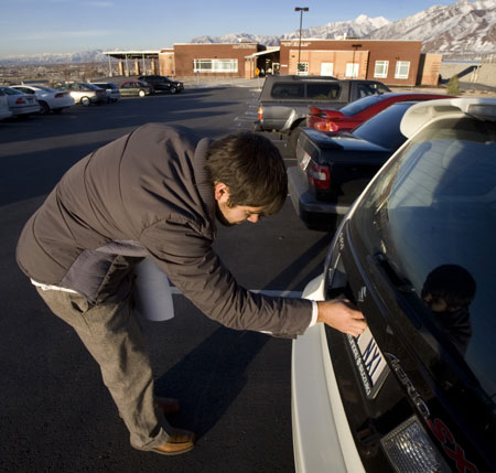 Brandon Burns, of Lehi, UT, places renewal stickers on his license plate after visiting the Utah Department of Motor Vehicles office just before closing time on Thursday, February 19, 2009, in Draper, Utah. (AP/Douglas C. Pizac)