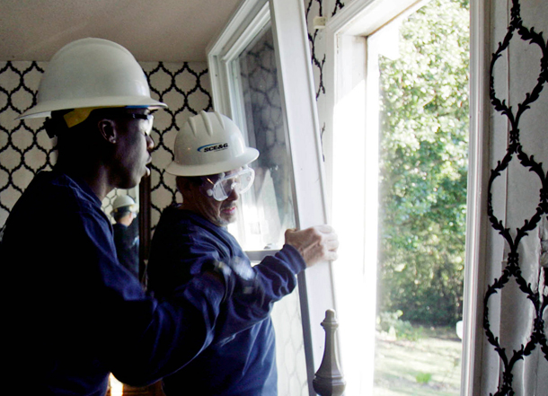 Two workers install energy efficient windows in a home in West Columbia, SC. The American Clean Energy and Security Act would provide up to $65 billion from 2012 to 2020 for state and local government energy efficiency programs. (AP/Mary Ann Chastain)