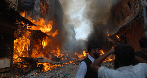 People gather at the site of a car bomb attack in Peshawar, Pakistan that killed 90 people. (AP/Mohammad Iqbal)