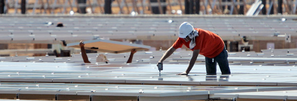 A worker secures a solar energy panel at a solar field under construction in Rancho Cordova, CA on September 15, 2009. Clean energy offers hope for the U.S. economy, but we need a comprehensive clean-energy strategy to start putting Americans back to work. (AP/Rich Pedroncelli)
