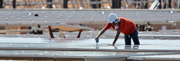 A worker secures a solar energy panel at a solar field under construction in Rancho Cordova, CA on September 15, 2009. Clean energy offers hope for the U.S. economy, but we need a comprehensive clean-energy strategy to start putting Americans back to work. (AP/Rich Pedroncelli)