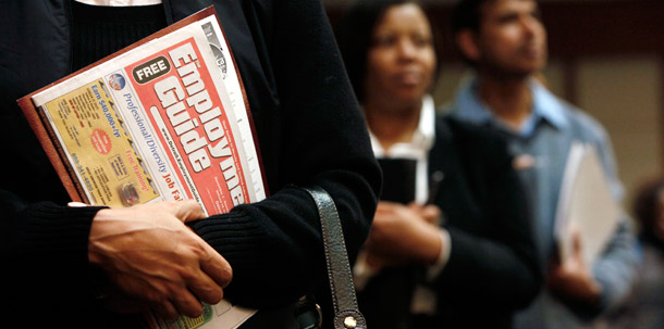 A woman holds an Employment Guide while standing in line while attending a job fair in Livonia, Michigan. (AP/Paul Sancya)