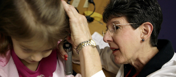 A pediatrician in San Angelo, Texas examines the ears of a patient that is enrolled in the state subsidized health care program. (AP/Patrick Dove)