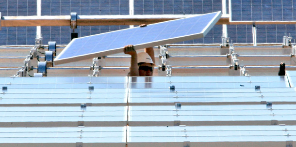 A construction worker places a solar energy panel in a solar energy field under construction in the Sacramento Municipal Utility District in Rancho Cordova, California. (AP/Rich Pedroncelli)