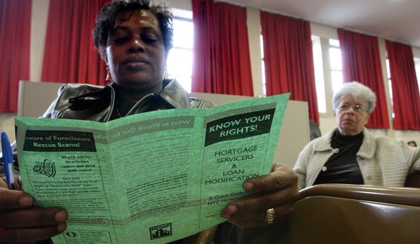 A woman reads a brochure as she waits to attend a workshop called "The Housing Crisis: How it Affects You, How it Affects our Neighborhood" in Queens, New York. (AP/Tina Fineberg)