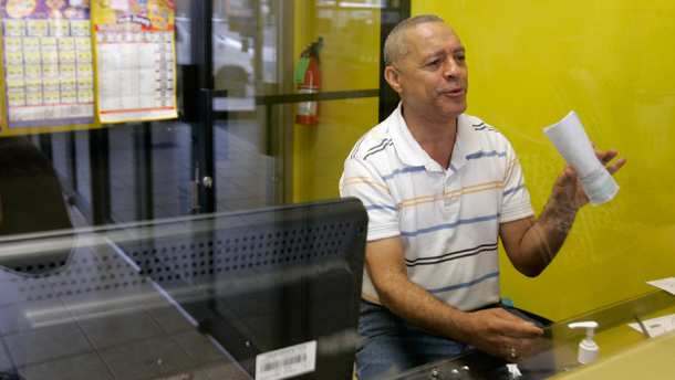 The manager of Tenares Communications, a Western Union office in Passaic, New Jersey, holds up remittance checks that were sent from foreign countries to immigrants in the United States. Money transfer agencies have been reporting a continuing decline in the amount of money immigrants in the United States are sending to relatives back home. (AP/Mike Derer)
