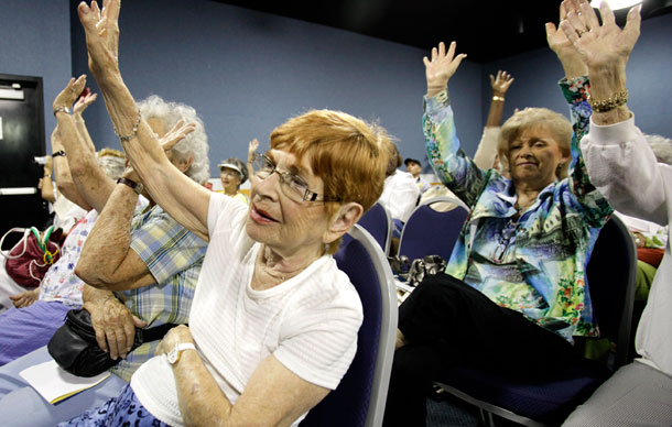 Marilynn Garfield of Delray Beach, FL, left, raises her hand when the audience was asked how many are on Medicare during the Florida Alliance for Retired Americans fifth annual town hall meeting on health care reform in Delray Beach, FL. (AP/Lynne Sladky)