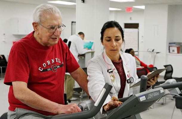 Cleveland Clinic exercise physiologist Audra DiRauso sets up an exercise bike for Anthony Rugare during a cardiac rehabilitation class on December 21, 2009, in Cleveland. Medicare and Medicaid—like private coverage sources—are buffeted by the larger health care market, including the demand for services and the changes in technologies, prices, and utilization patterns. (AP/Haraz N. Ghanbari)