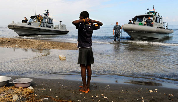 A photo provided by the US Navy shows a Haitian boy watching as rigid-hull inflatable boats from the amphibious dock landing ships USS Fort McHenry and USS Carter Hall arrive ashore on January 19, 2010 at the New Hope Mission at Bonel, Haiti. (AP/U.S. Navy /Kristopher Wilson)
