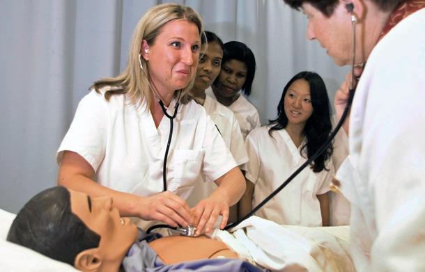 Nursing students use a double stethoscope on a practice dummy with instructor Julie Bliss, right, during a nursing class at William Paterson University in Wayne, New Jersey. (AP/Mike Derer)