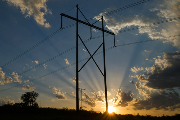 An older transmission power track and power line stands tall against a Kansas sunset north of Topeka, Kansas. Utilities are vying to build a new power system to stretch across the state that would give six times more capacity than the present systems. The upgraded systems will be needed to help fully harness wind power generation. (AP/Chuck France)