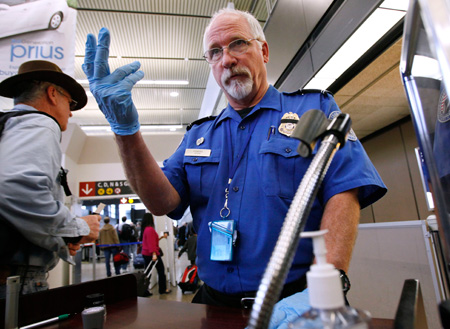 A TSA officer signals an airline passenger forward at a security check-point at Seattle-Tacoma International Airport on Monday, January 4, 2010. (AP/Elaine Thompson)