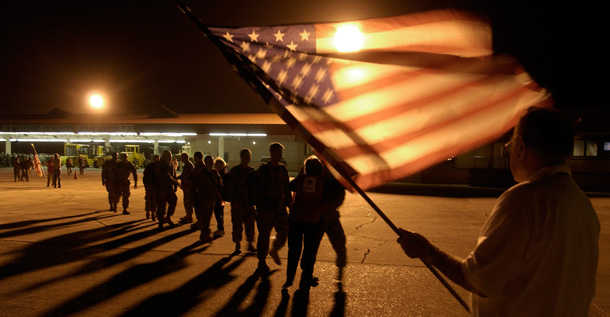 A member of the USO waves a flag as he welcomes home members of the Georgia National Guard. (AP/Stephen Morton)