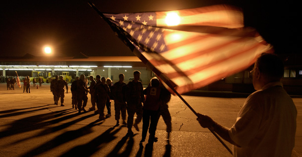 A member of the USO waves a flag as he welcomes home members of the Georgia National Guard. (AP/Stephen Morton)