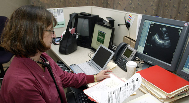 Dr. Sheila Gamache goes over paper records in an exam room at the Indiana Heart Hospital in Indianapolis. The hospital is "paperless" but still faces the challenge of working with patients referred from other hospitals that use paper records. (AP/Michael Conroy)
