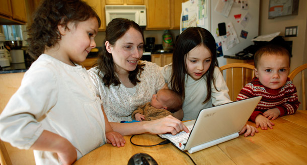 Kristie McNealy works on her laptop computer while her children join her at the dining room table in the family's home in Aurora, Colorado. (AP/David Zalubowski)