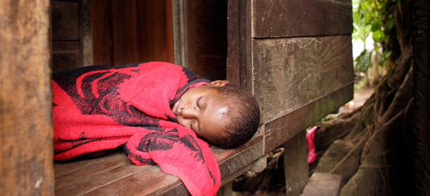A young Papua New Guinean girl, who is believed to have contracted malaria, sleeps on the front porch of her bayside shack. Scientists report that malaria will begin spreading to new areas as the climate warms. (AP/David Longstreath)
