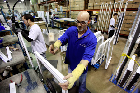 Workmen build windows at a factory in Philadelphia. The economic recovery is spreading and merchants are seeing better sales and factories are boosting production, but many companies are still wary of ramping up hiring. (AP/Matt Rourke)