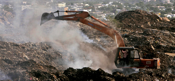 A crane segregates waste in a dump yard on the outskirts of Hyderabad, India. Major greenhouse gas and energy-intensive industries in the United States and the European Union are worried that relative inaction on the part of certain major emitting developing countries such as India will produce competitive challenges. (AP/Mahesh Kumar A)